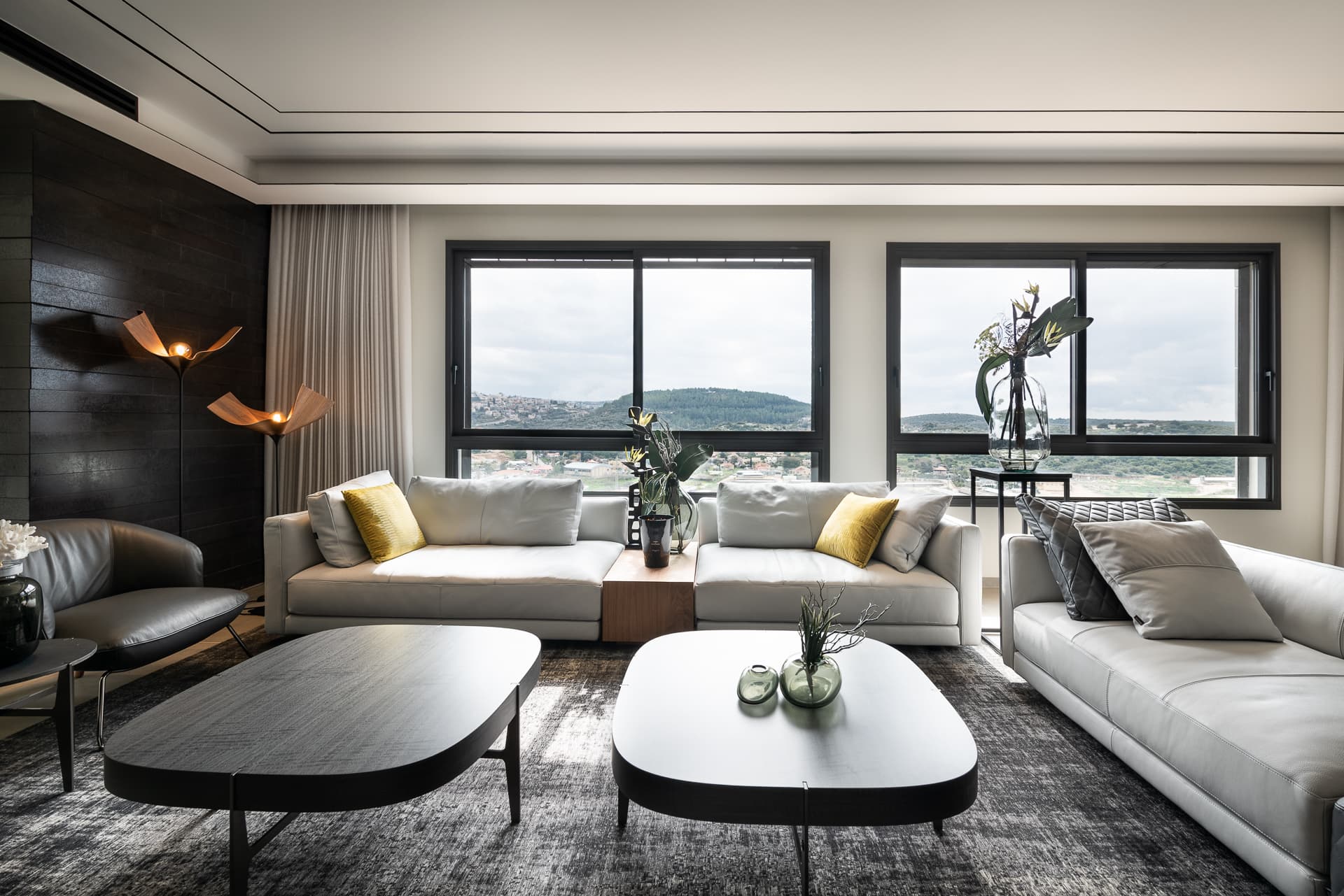 Pale grey leather sofas, oval dark coffee tables and folded copper floor lamps before wide windows in the living room of Timeless Union