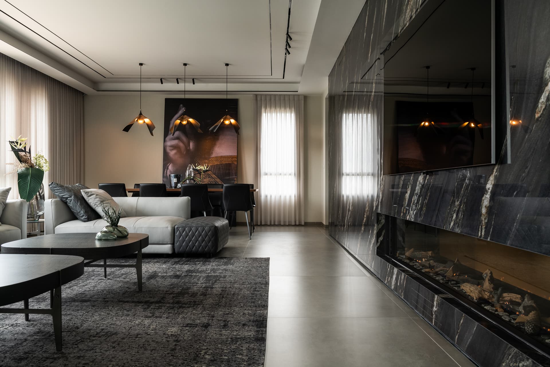 Black veined stone wall with a long linear fireplace running beside the seating and dining zones in the living room of Timeless Union