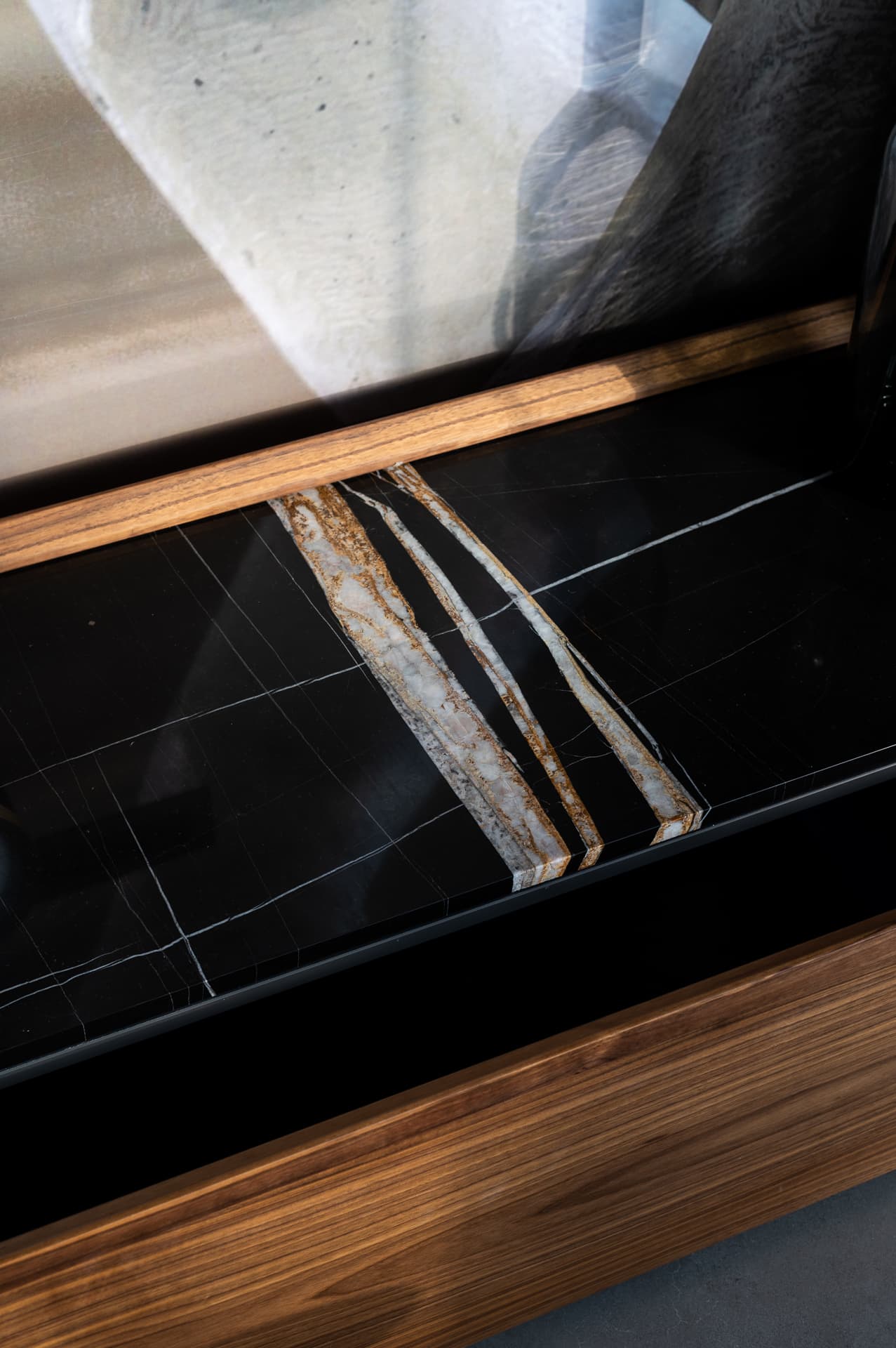 Black stone with bold golden veins set into a walnut frame on a bedside surface in the master bedroom of Timeless Union