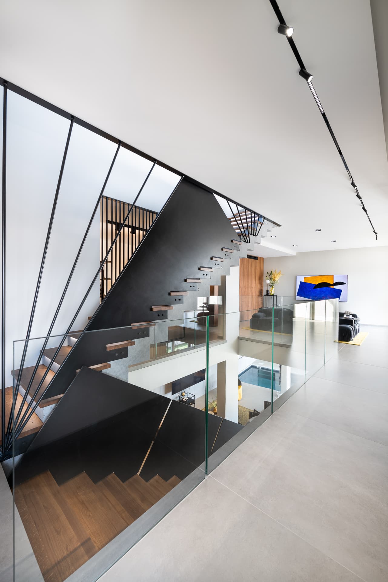 Folded black steel stair with fanned rod balustrade and oak treads beside a glass-railed landing in Timeless Union