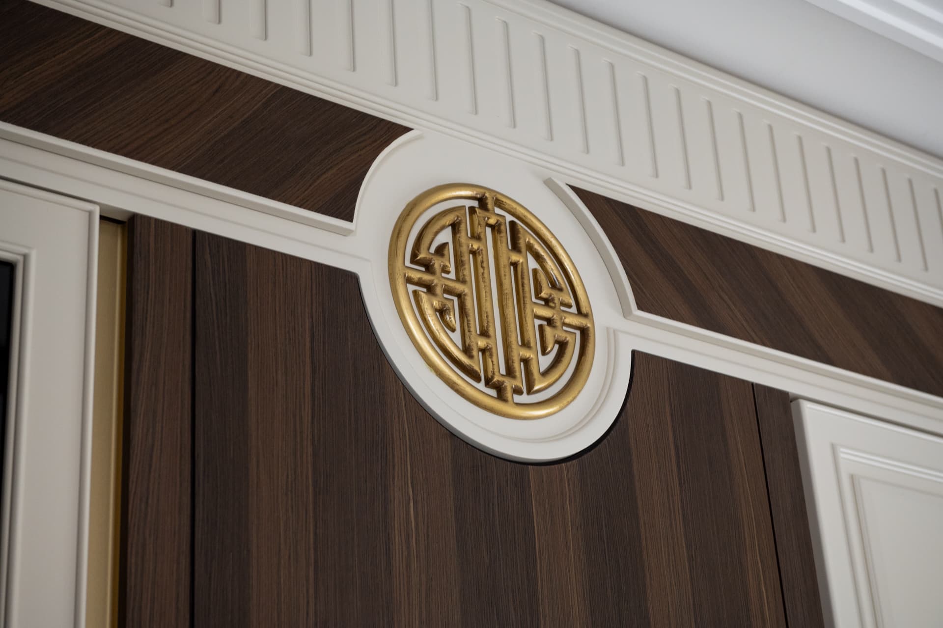 Gilded circular lattice medallion set into a cream fluted cornice over dark wood wall panelling in the dining room of Twilight