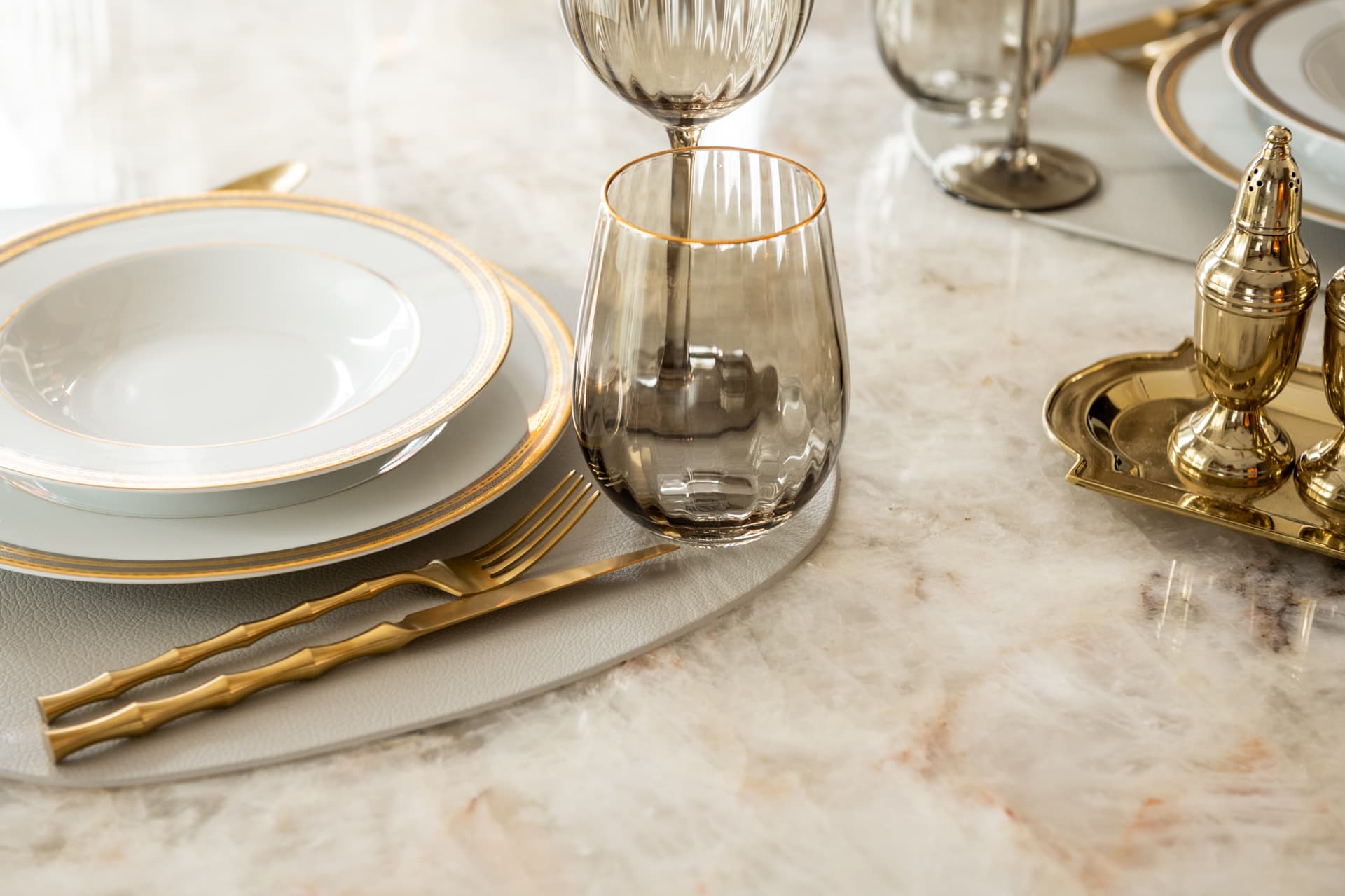 Gold-rimmed china, smoked ribbed glassware and bamboo-style gold cutlery on a veined stone table in the dining room of Twilight